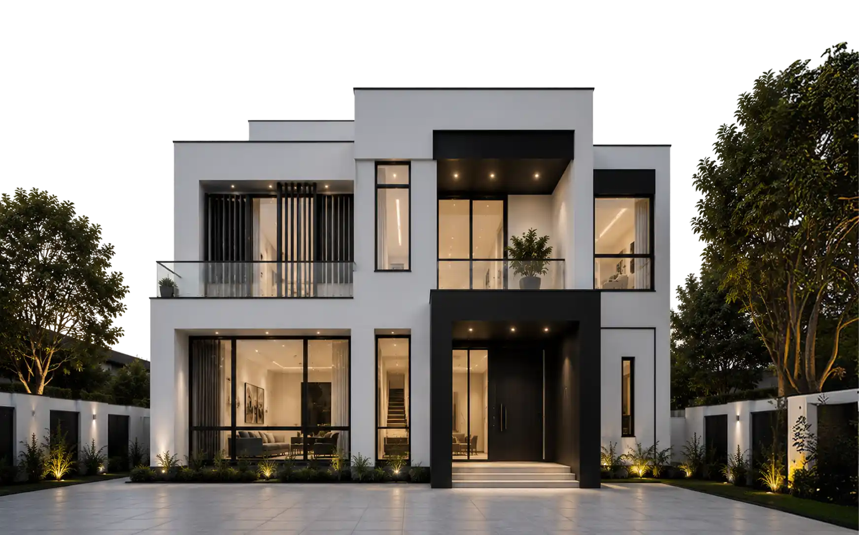 Modern two-story house with white walls and black accents is lit warmly at night, featuring large glass windows, a front entrance with stairs, balconies with glass railings, and landscaping with trees and shrubs along a tiled driveway.